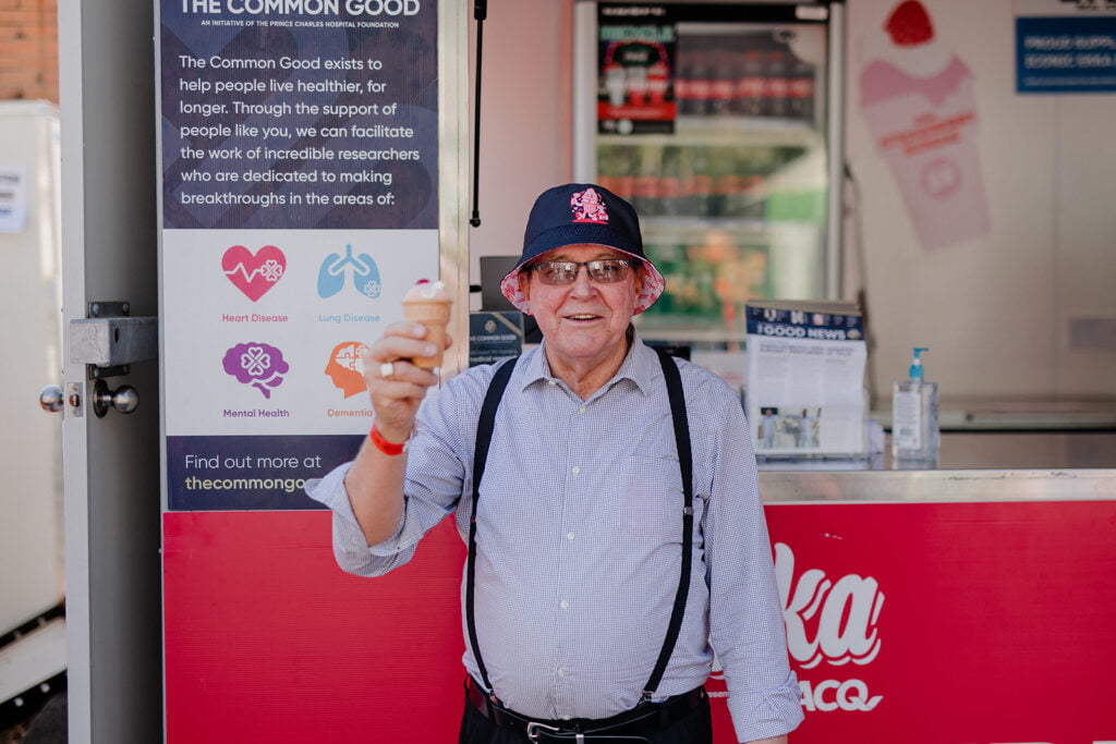 Volunteer Allan holding up a strawberry sundae outside of a stand at the Ekka 2023